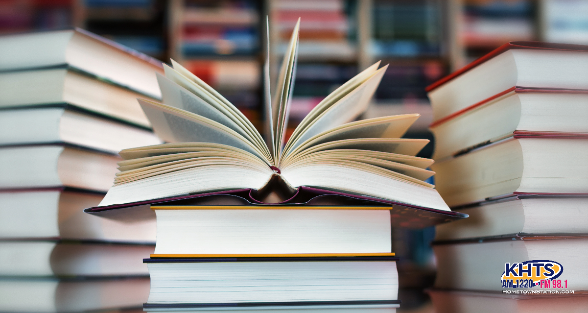 Image of an open library book against a blurred background of other library books. 